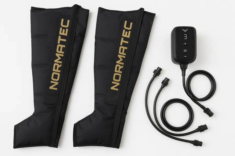 Hyperice Normatec 3 Legs compression boots in black with control unit, laid out on a wooden floor