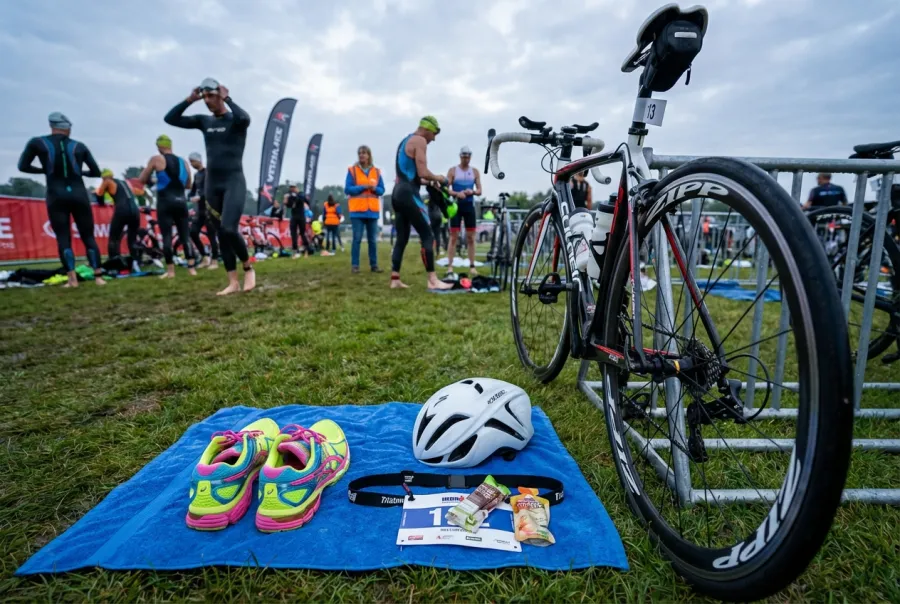 Organized triathlon transition area with helmet, shoes, and race belt laid out on a towel next to a bicycle