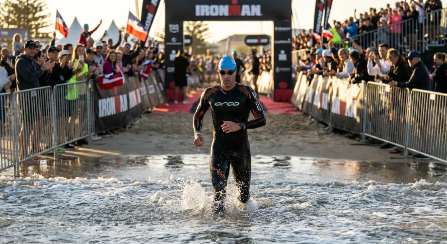 Triathlete in Orca wetsuit running out of the open water at a triathlon race