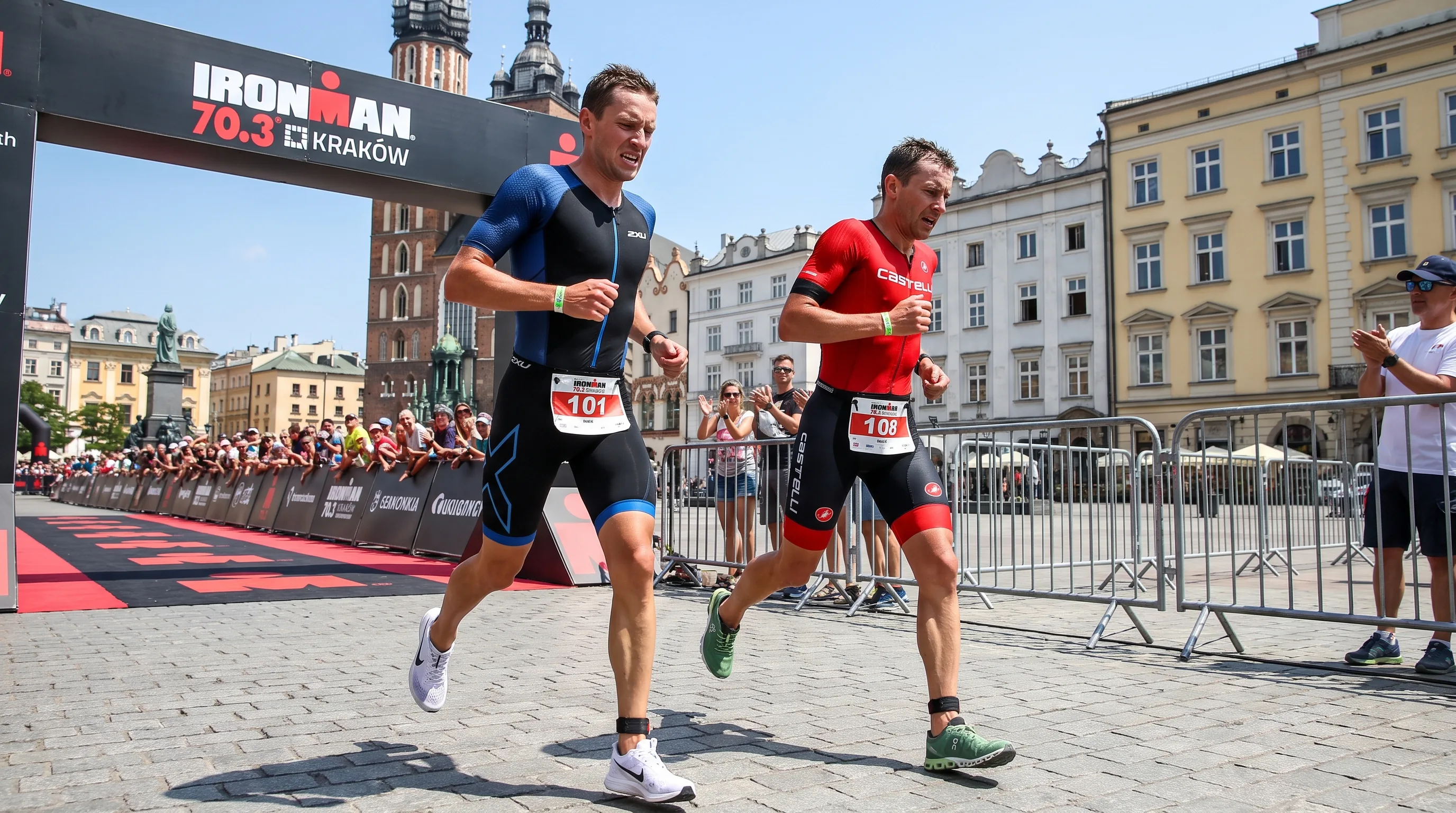Two elite triathletes in a tight sprint finish on the run course near a European old-town square, one athlete edging ahead in the final meters