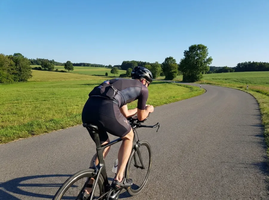 Triathlete riding confidently on a bicycle during an IRONMAN race on a scenic road course