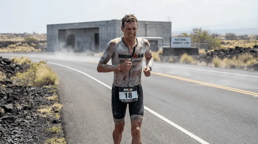 Lone triathlete running through the desolate Energy Lab section of the Kona Ironman marathon in harsh Hawaiian midday heat