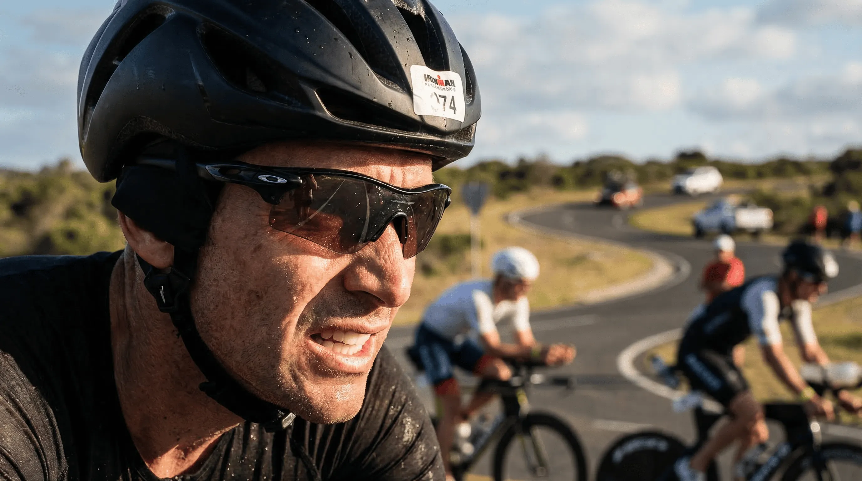 Tight portrait of a triathlete's face showing intense focused concentration during the Ironman bike leg wearing an aero helmet