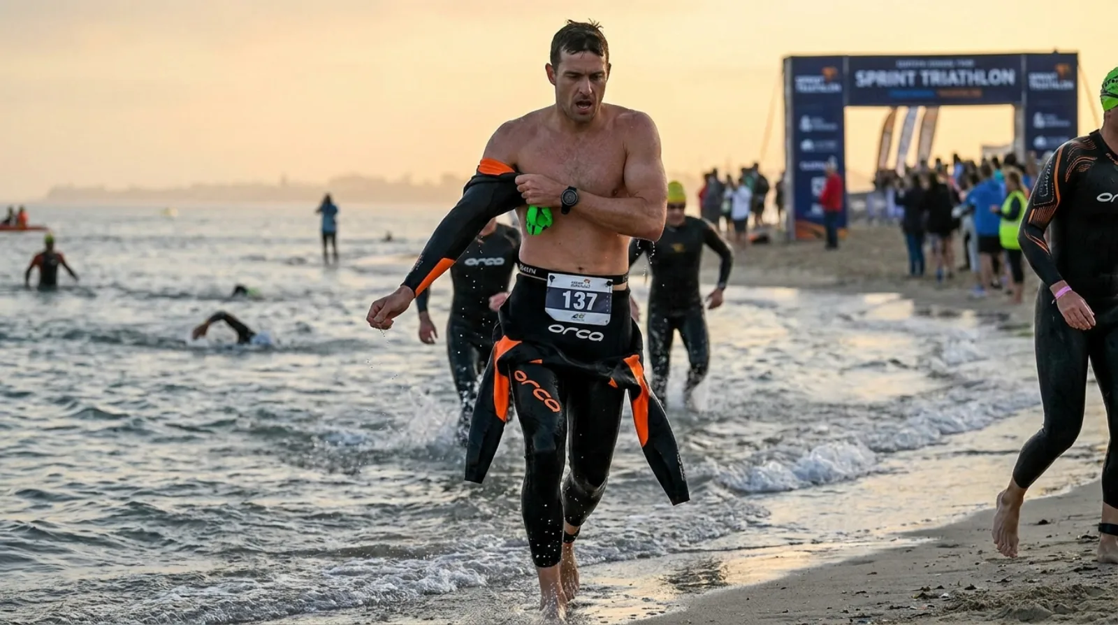 Triathlete sprinting out of open water at the start of a sprint triathlon
