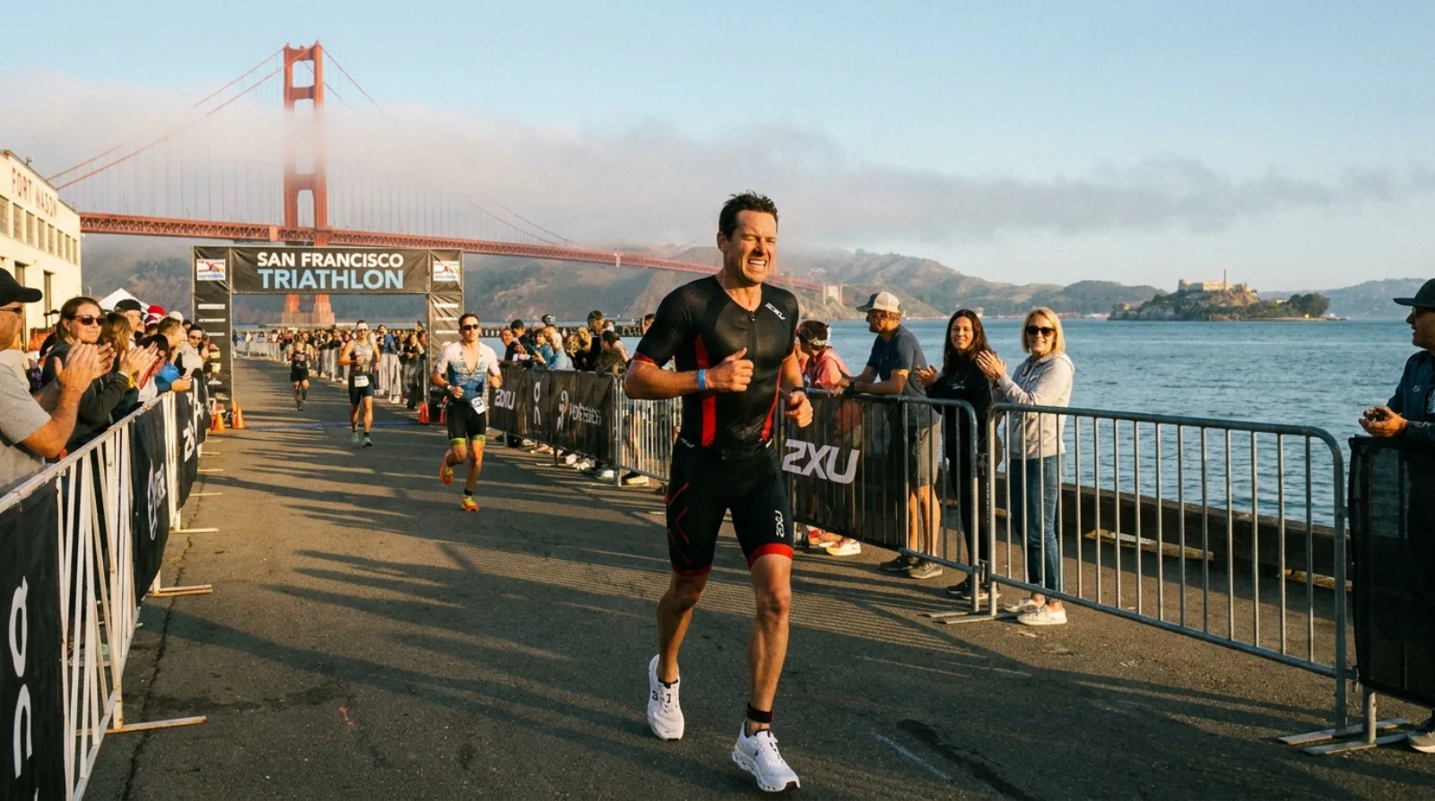 Triathlete in 2XU kit running through San Francisco waterfront with Alcatraz Island visible in the bay