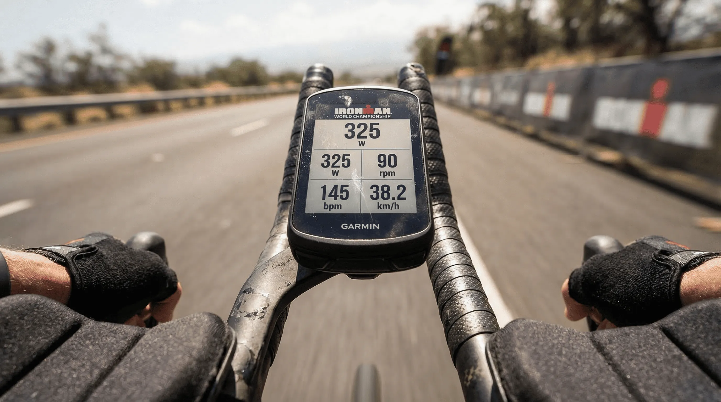 Close-up of Garmin cycling computer showing real-time power, heart rate and cadence data during an Ironman bike leg