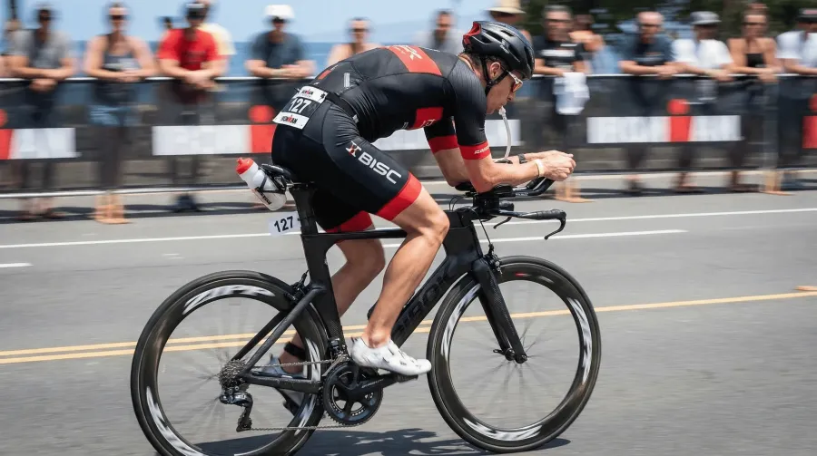 Triathlete in full aero position drinking through integrated hydration straw during an Ironman race