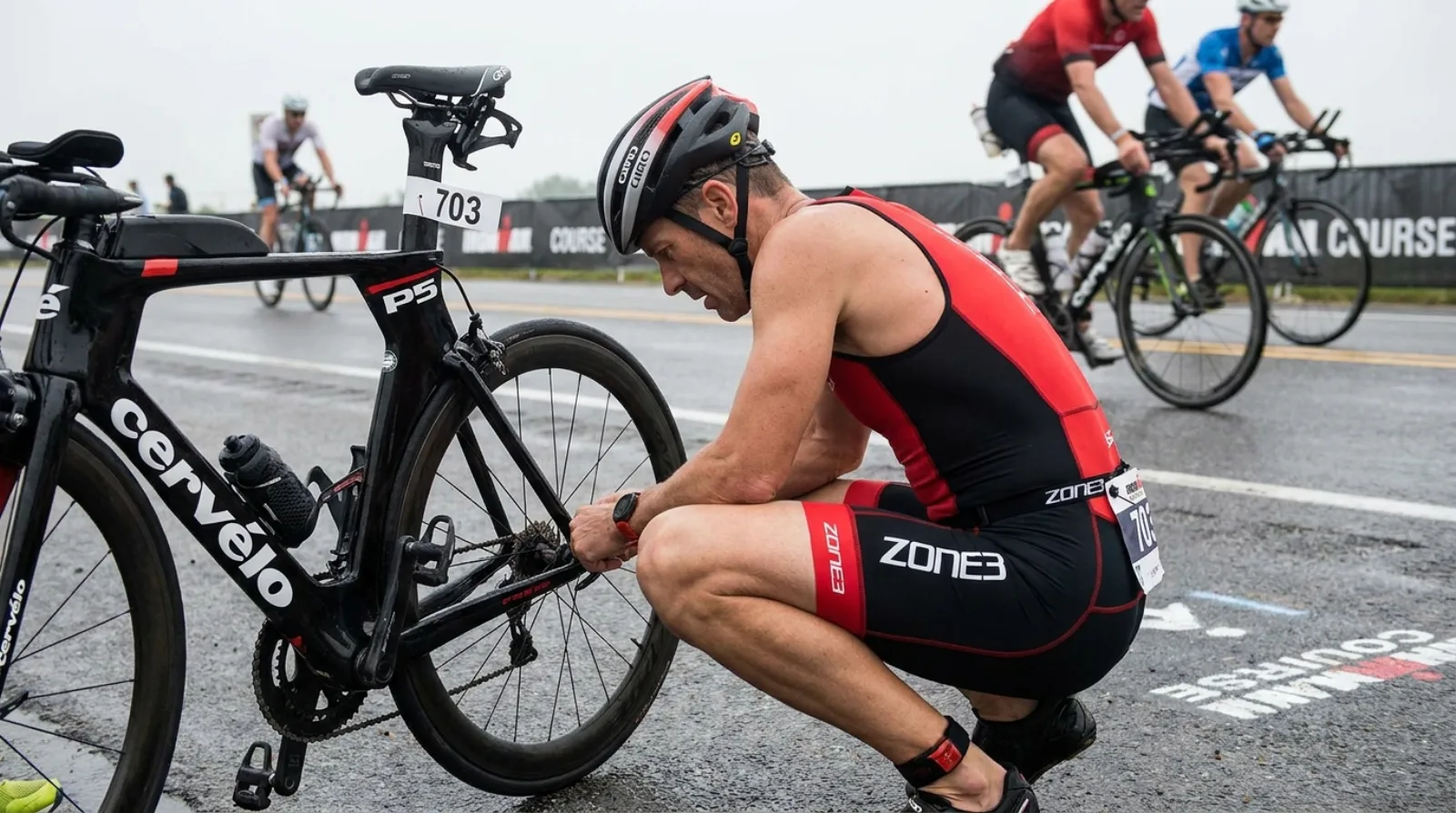 Triathlete fixing a flat tire on the side of an IRONMAN race course