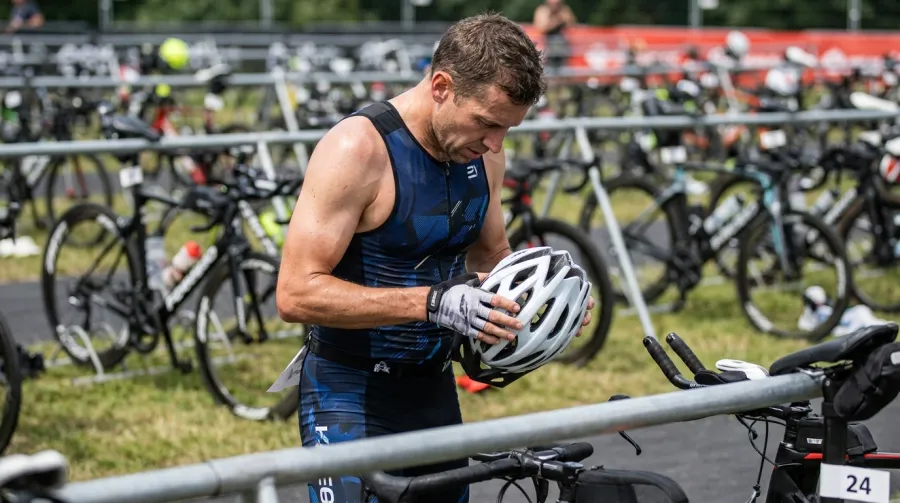 Triathlete examining helmet in the transition zone before a race